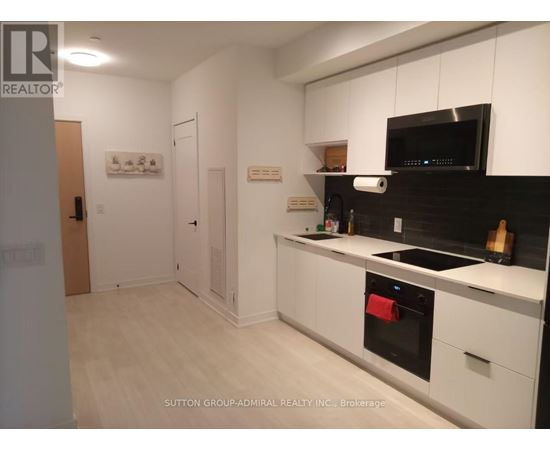 A kitchen with white cabinets and black countertops.
