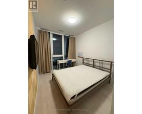 A bedroom with a bed, desk, and chair.