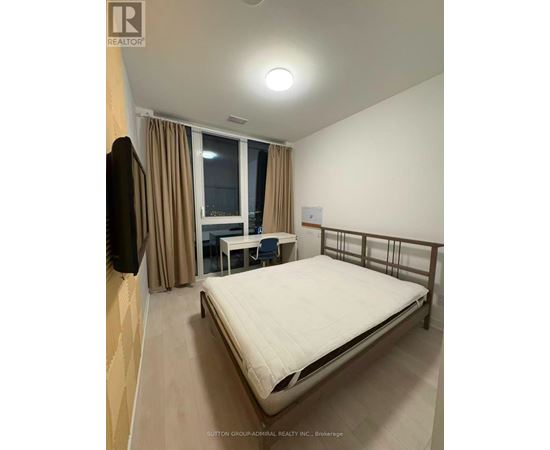 A bedroom with a bed, desk, and chair.