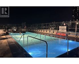 A pool on a rooftop at night with a sign that says "REALTOR".