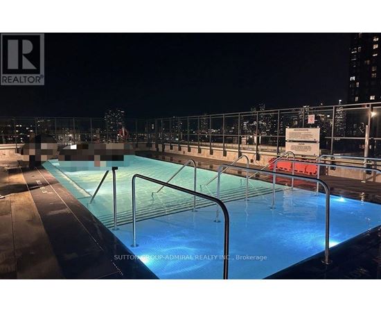A pool on a rooftop at night with a sign that says "REALTOR".