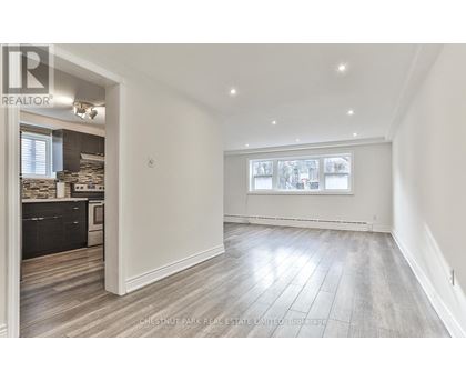 A spacious room with wood flooring and a large window.