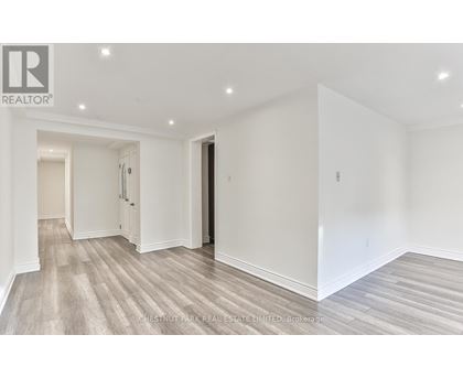 A spacious room with wood flooring and white walls.