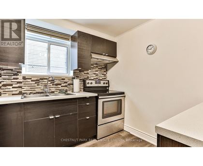 A kitchen with a stone backsplash and a stove top oven.