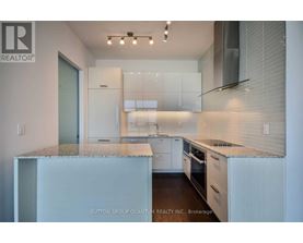 A modern kitchen with white cabinets and a marble countertop.
