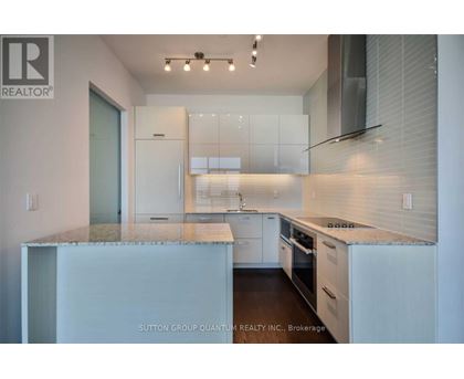 A modern kitchen with white cabinets and a marble countertop.