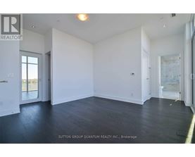 A spacious room with white walls and dark wood flooring.