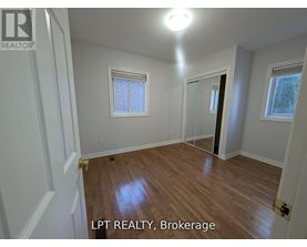A room with wooden flooring and white walls, with a window and a door visible.