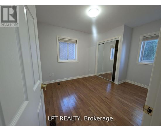 A room with wooden flooring and white walls, with a window and a door visible.