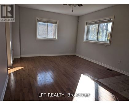 A room with wooden flooring and two windows.