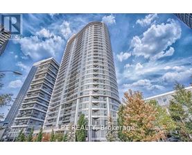 A tall building with a curved facade stands in front of a cloudy sky.