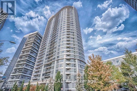 A tall building with a curved facade stands in front of a cloudy sky.