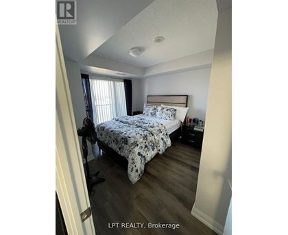 A bedroom with a bed, nightstand, and window.