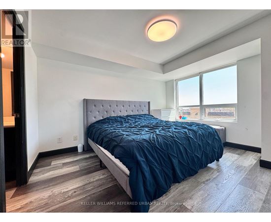 A bedroom with a bed, a window, and a wooden floor.