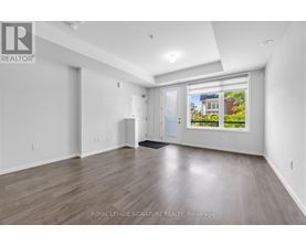 A spacious room with wooden flooring and white walls, with a window showing an outdoor view.
