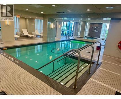 A large indoor swimming pool with a glass bottom and a metal ladder.