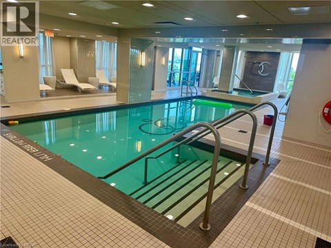A large indoor swimming pool with a glass bottom and a metal ladder.