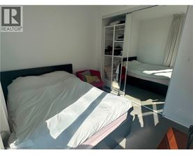 A bedroom with a bed, a mirror, and a wardrobe.