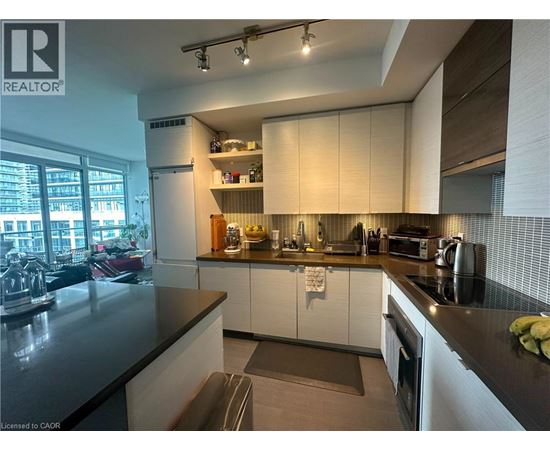 A modern kitchen with white cabinets and black countertops.