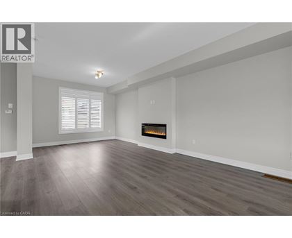 A spacious living room with a fireplace and wood flooring.