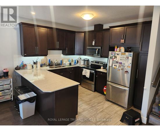 A kitchen with a refrigerator, stove, and microwave.