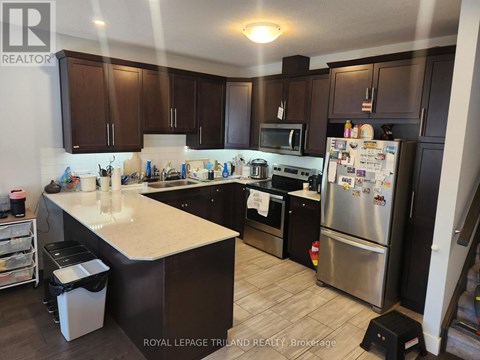 A kitchen with a refrigerator, stove, and microwave.