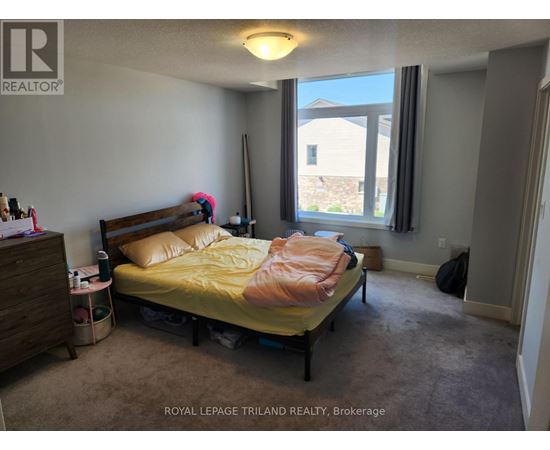 A bedroom with a bed, nightstand, and window.