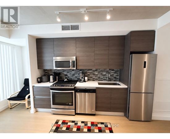 A modern kitchen with a refrigerator, oven, and sink.