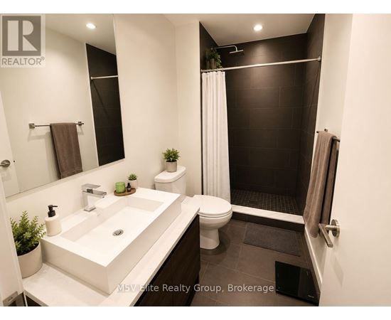 A bathroom with a white sink and black tiles.