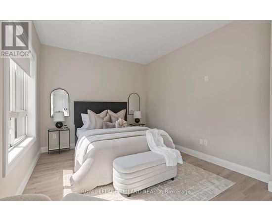 A bedroom with a large bed and a nightstand with a lamp.