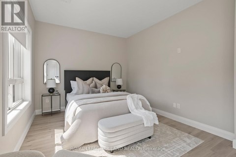 A bedroom with a large bed and a nightstand with a lamp.