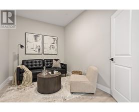 A living room with a black leather sofa, a wooden coffee table, and a beige armchair.