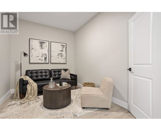A living room with a black leather sofa, a wooden coffee table, and a beige armchair.