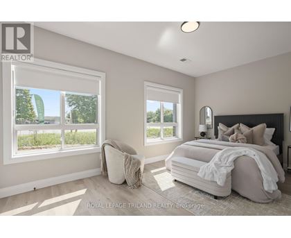 A bedroom with a large bed and two windows.