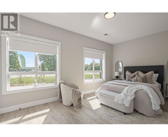 A bedroom with a large bed and two windows.