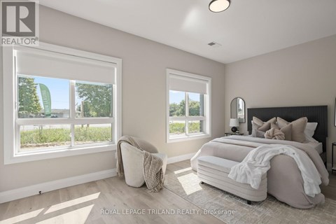 A bedroom with a large bed and two windows.
