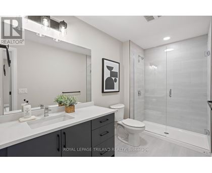 A white bathroom with a toilet, sink, and mirror.