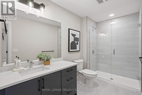 A white bathroom with a toilet, sink, and mirror.