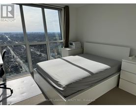 A bedroom with a large bed and a view of the city from the window.