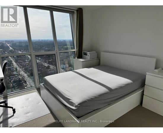 A bedroom with a large bed and a view of the city from the window.