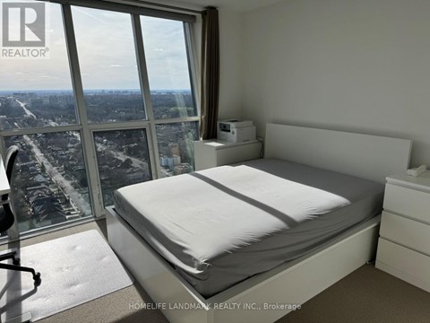 A bedroom with a large bed and a view of the city from the window.