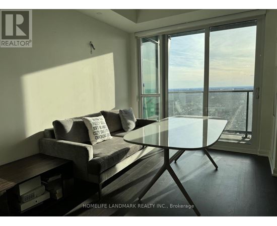 A living room with a grey couch and a glass table.