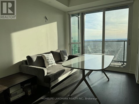 A living room with a grey couch and a glass table.