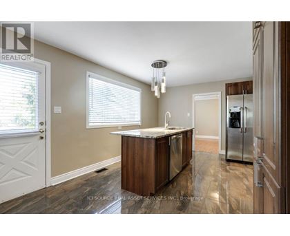 A kitchen with a wooden island and a refrigerator in the background.