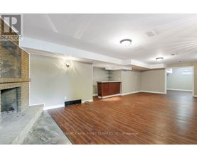 A spacious room with a fireplace and wooden flooring.