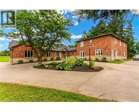 A red brick house with a driveway and a tree in front.