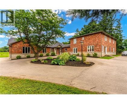 A red brick house with a driveway and a tree in front.