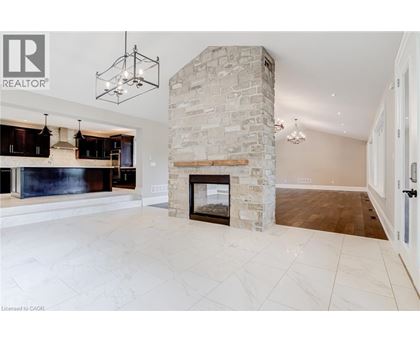 A spacious living room with a stone fireplace and a large painting above it.