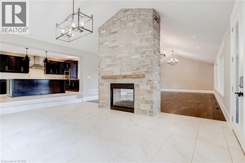 A spacious living room with a stone fireplace and a large painting above it.