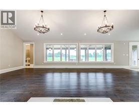 A spacious room with wooden floors and two chandeliers.